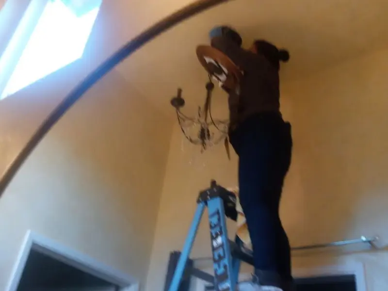 Electrician installing a chandelier in a Eldridge residence